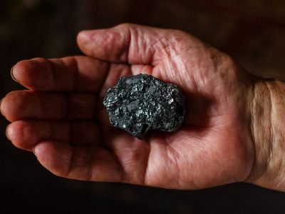Home Close-up view of a hand displaying a piece of coal. Ideal for energy or geology themes.