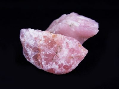 Home Detailed image of raw pink rose quartz stones against a black background, highlighting natural beauty.