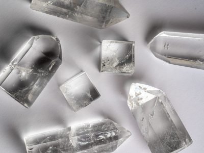 Home Clear quartz crystals arranged on a white surface, showcasing natural beauty and clarity.