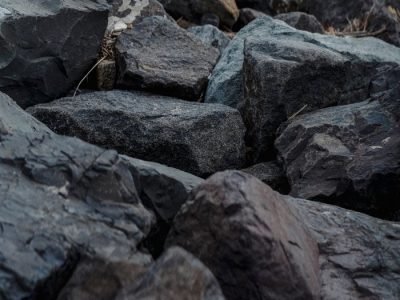 Home From above of rough dark stones placed on shore in nature in daytime